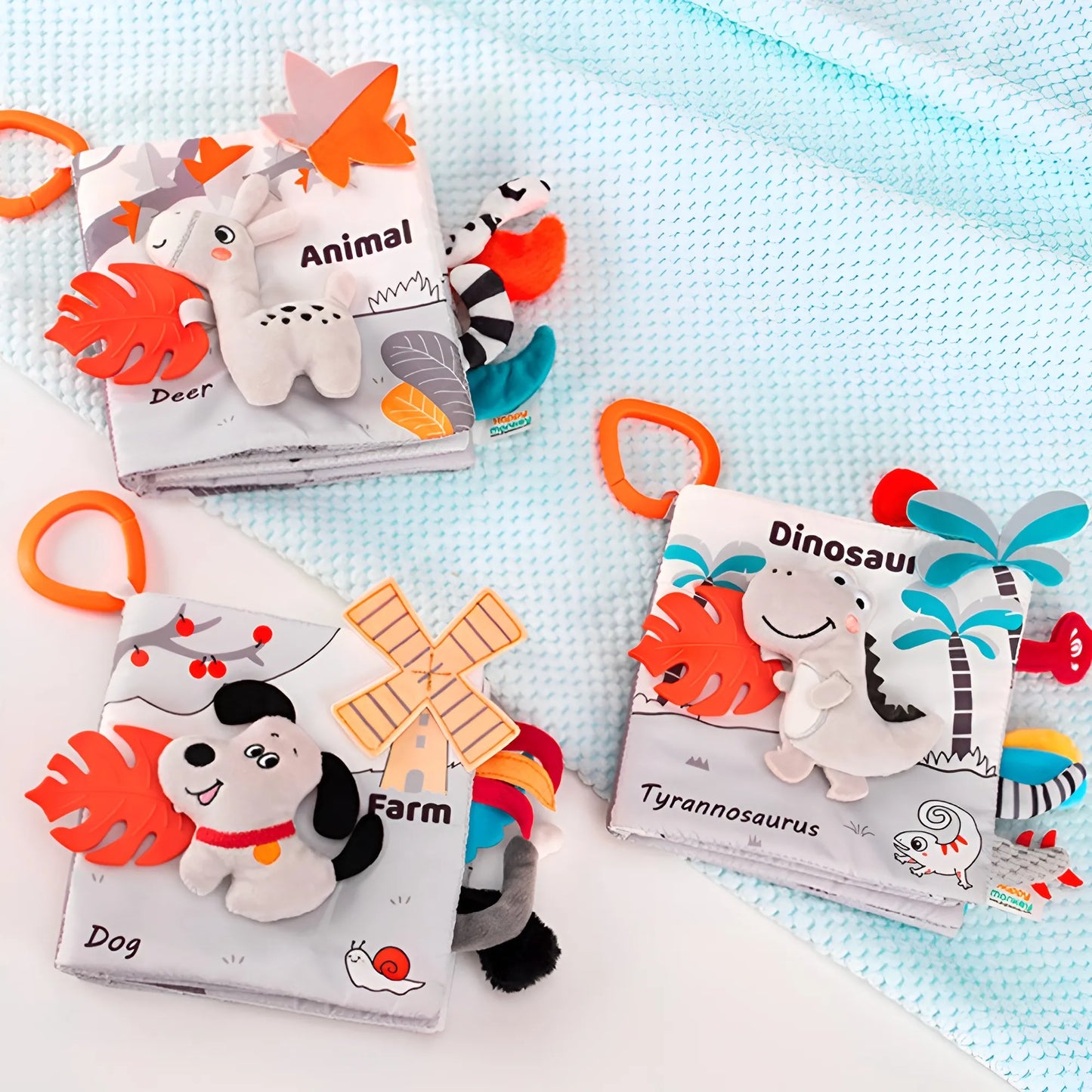 Three educational baby books with plush toys on a light blue blanket