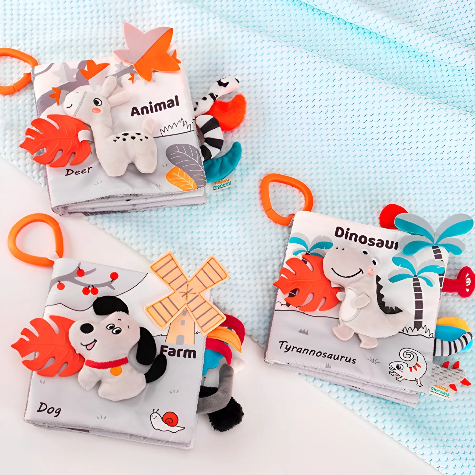 Three educational baby books with plush toys on a light blue blanket