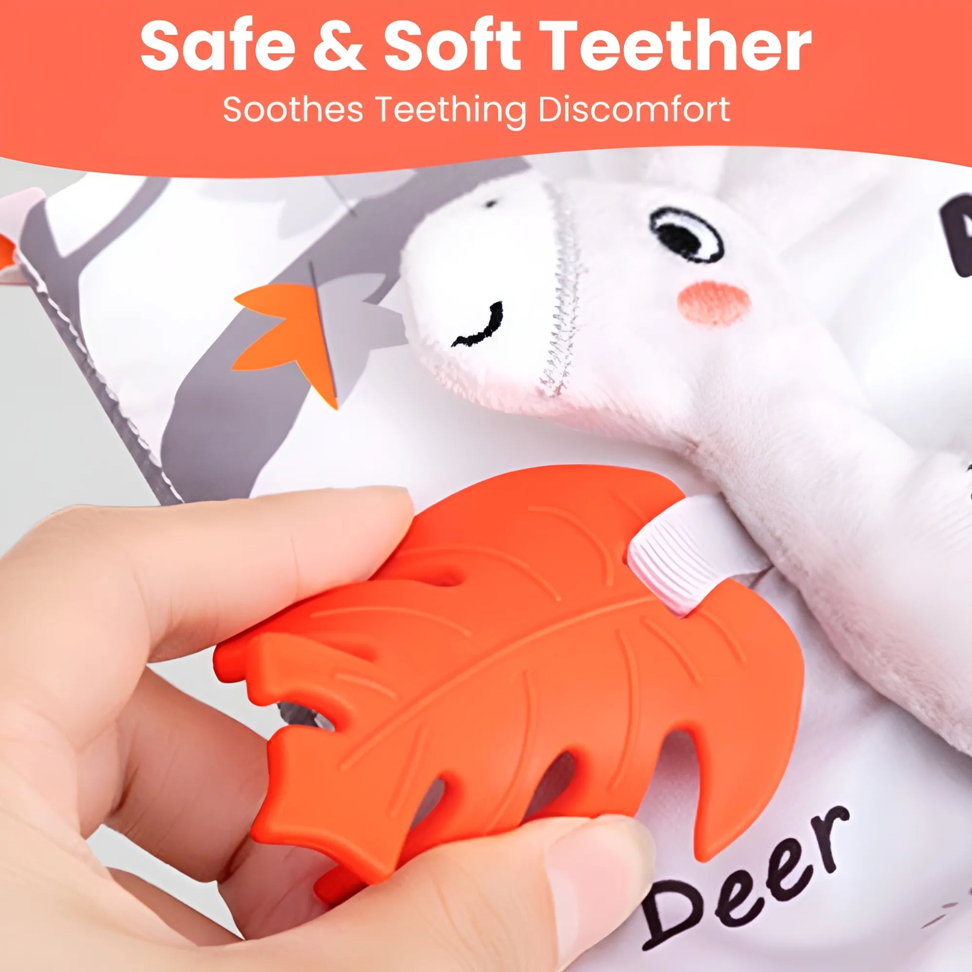 Orange teething toy shaped like a leaf held by a hand, with a white plush toy in the background.