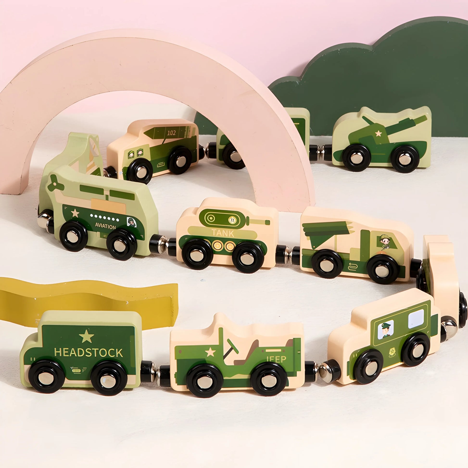 Set of magnetic green wooden toy trucks on a white surface with a pink arch and green cloud-like object in the background.