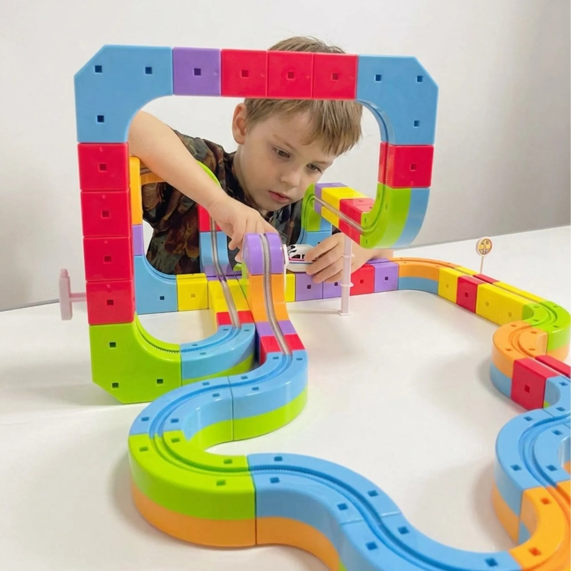 Child playing with Montessori 3D Electric Train Track toy on a white surface