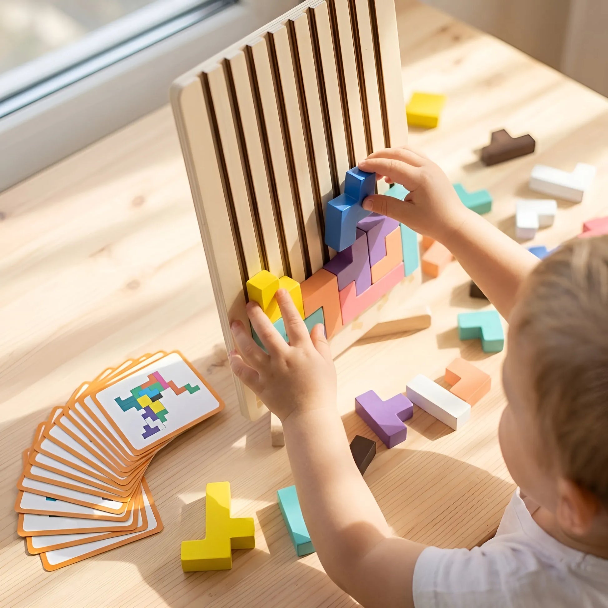 Child playing with colorful wooden building blocks on a wooden table.
